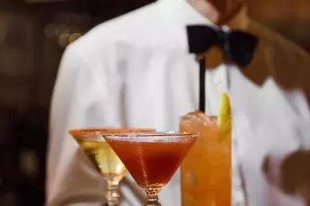 在贝博体彩app的苦艾酒餐厅，一个戴着蝴蝶结的服务员端着鸡尾酒盘。.